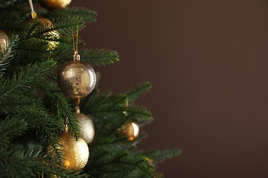 Photo of Beautifully decorated Christmas tree on brown background, closeup. Space for text