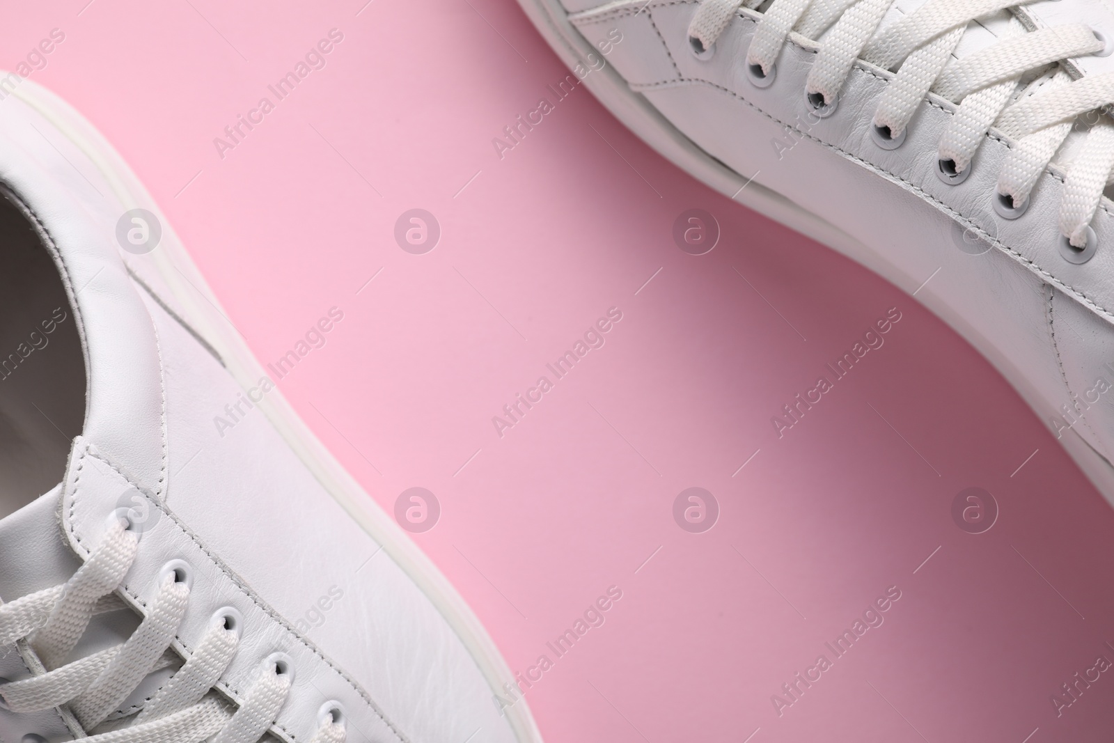 Photo of Pair of stylish white sneakers on pink background, top view. Space for text