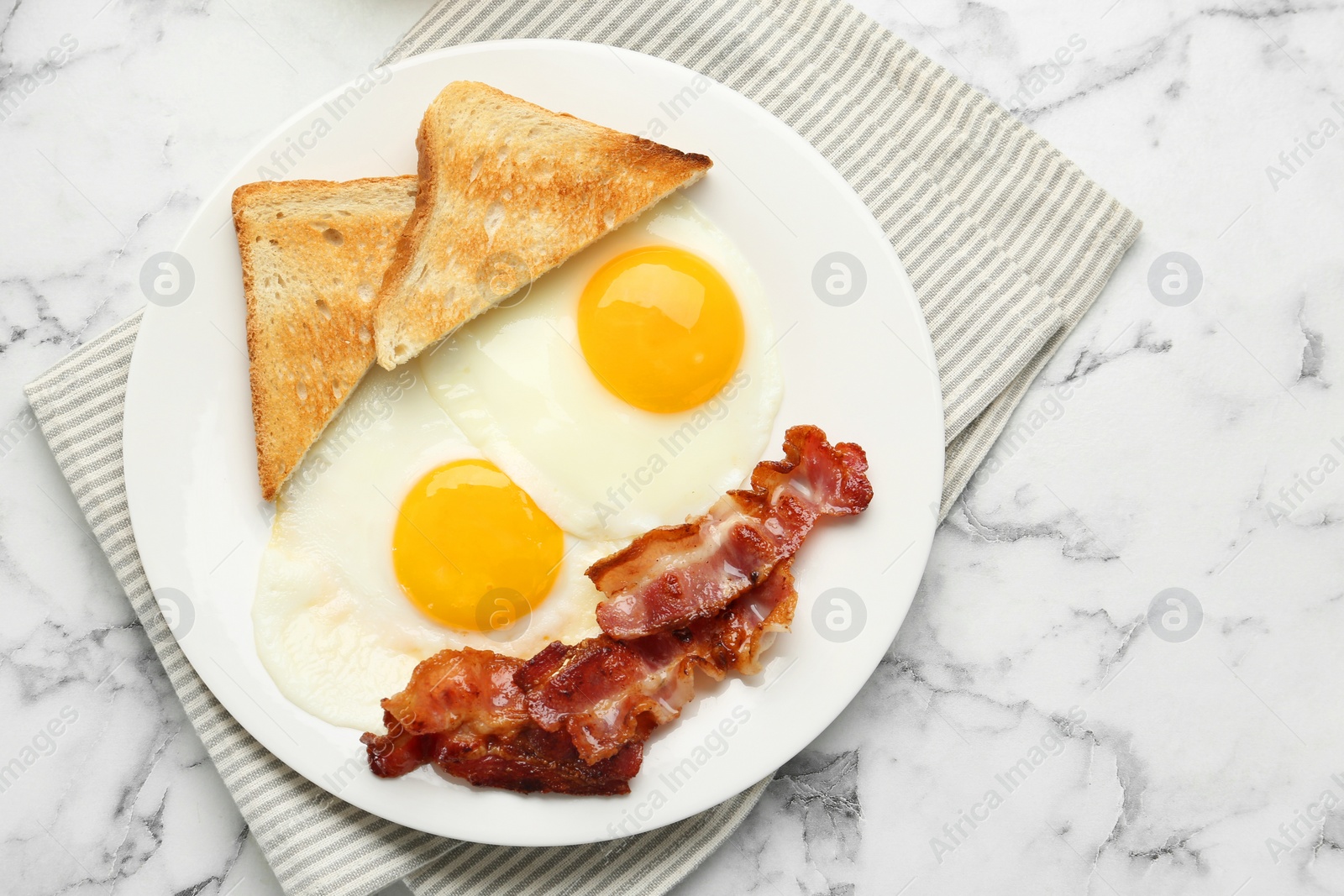 Photo of Delicious breakfast with sunny side up eggs on white marble table, top view