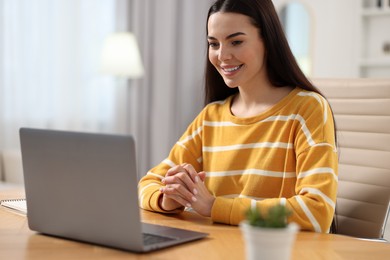 Young woman watching webinar at table in room