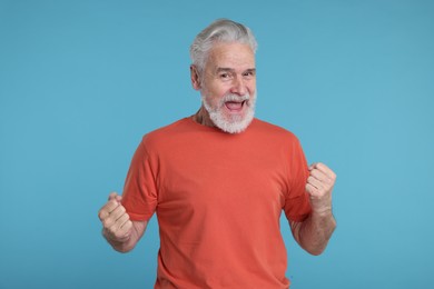 Photo of Portrait of surprised senior man on light blue background