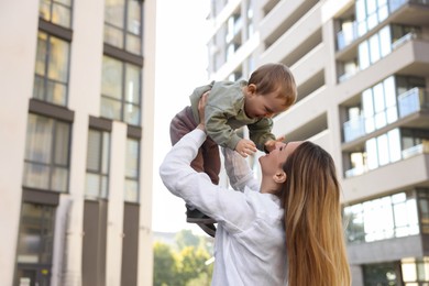 Photo of Happy nanny with cute little boy having fun outdoors, space for text