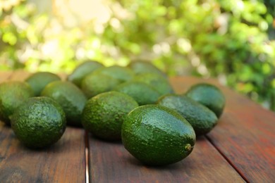 Tasty ripe avocados on wooden table outdoors
