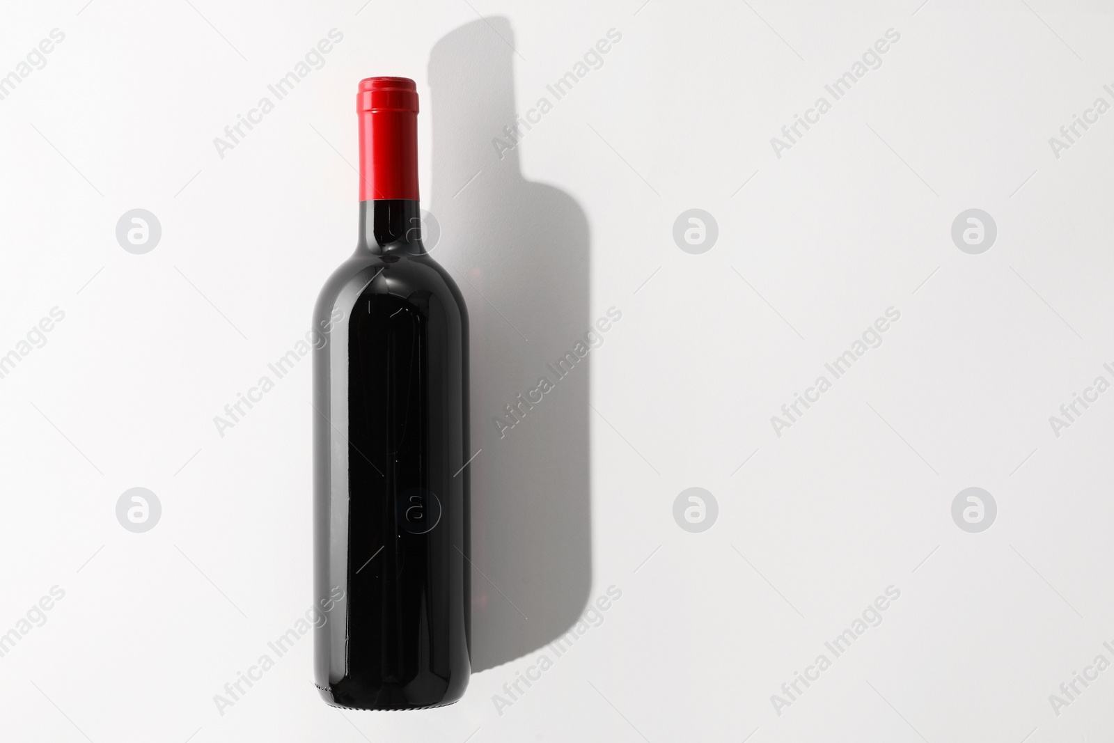 Photo of Bottle of expensive red wine on white background, top view. Space for text