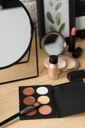 Photo of Mirror and makeup products on wooden dressing table, closeup