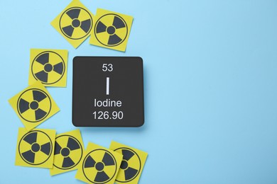 Photo of Card with chemical element Iodine and radiation signs on light blue background, flat lay. Space for text