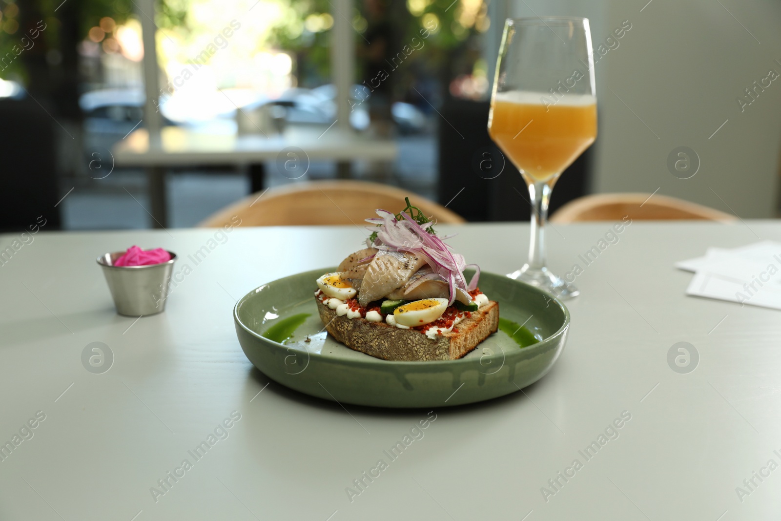 Photo of Tasty fish sandwich and glass of beer on light table