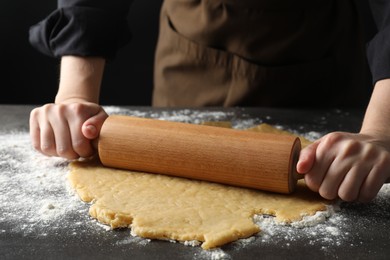 Photo of Making shortcrust pastry. Woman rolling raw dough at grey table, closeup