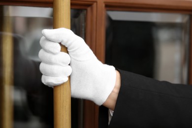 Butler in suit and white gloves opening hotel door, closeup