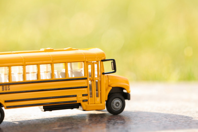 Photo of Yellow toy school bus outdoors on sunny day. Student's transport