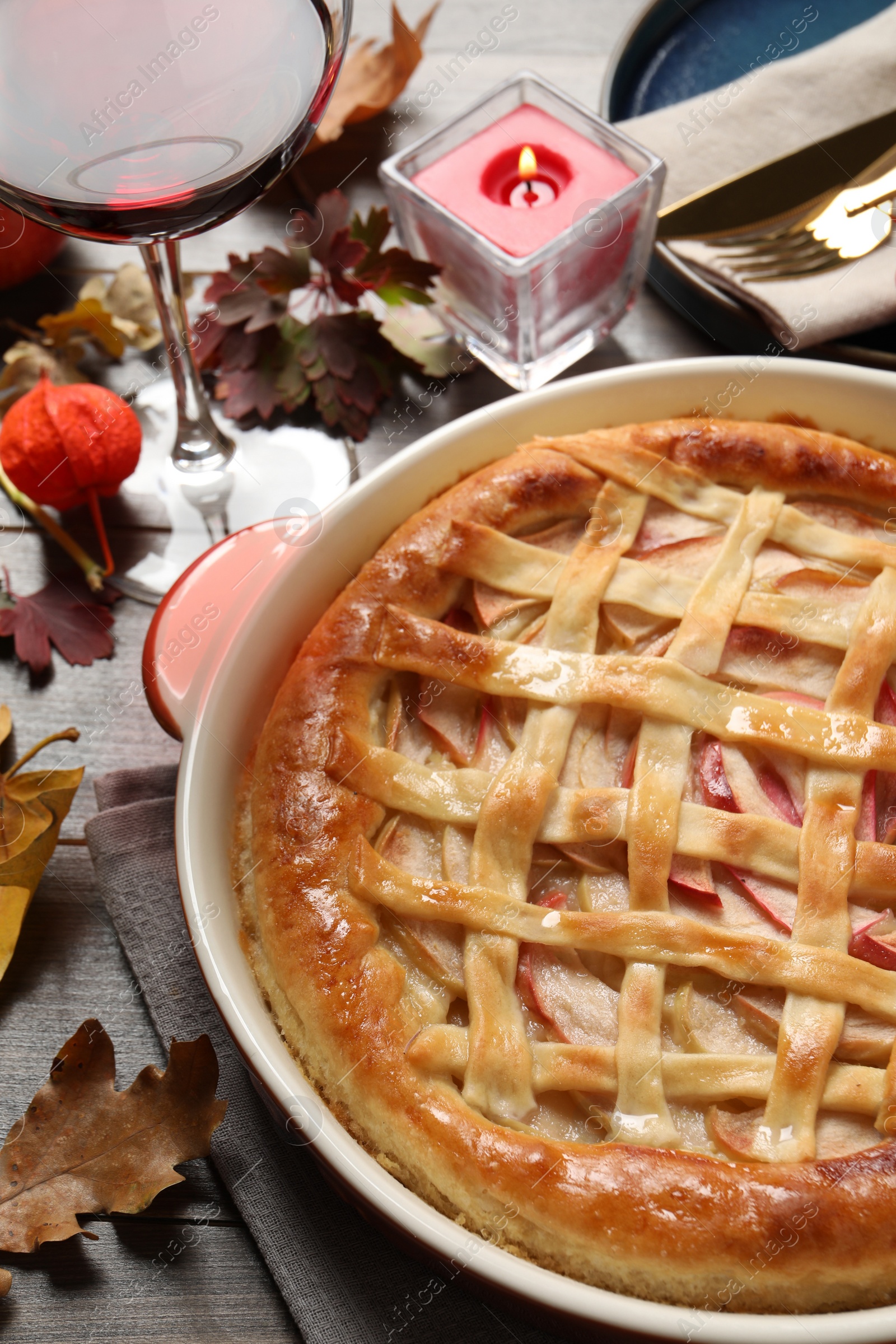 Photo of Delicious homemade apple pie and autumn decor on wooden table. Thanksgiving Day celebration