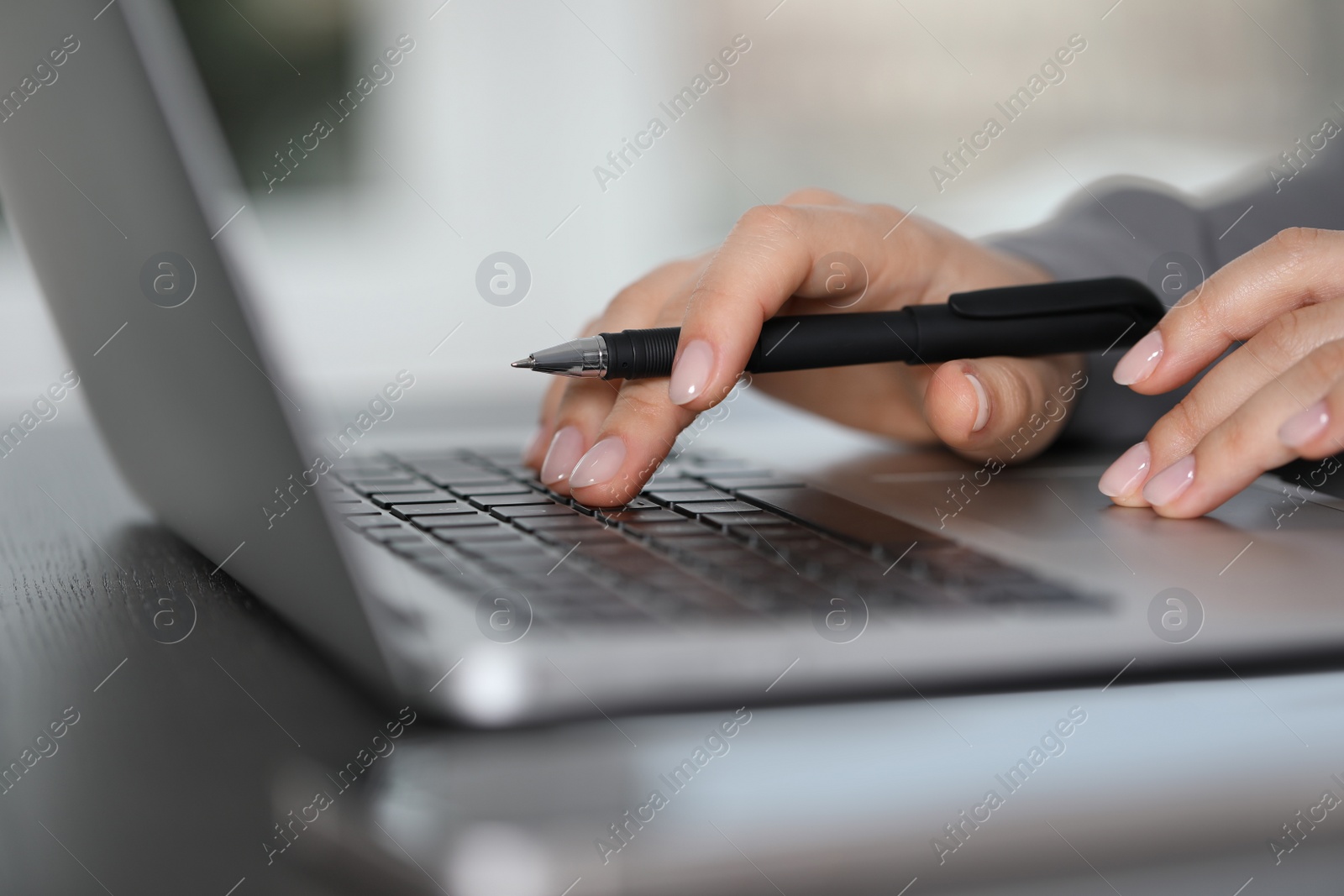 Photo of Woman working on laptop at table, closeup. Electronic document management