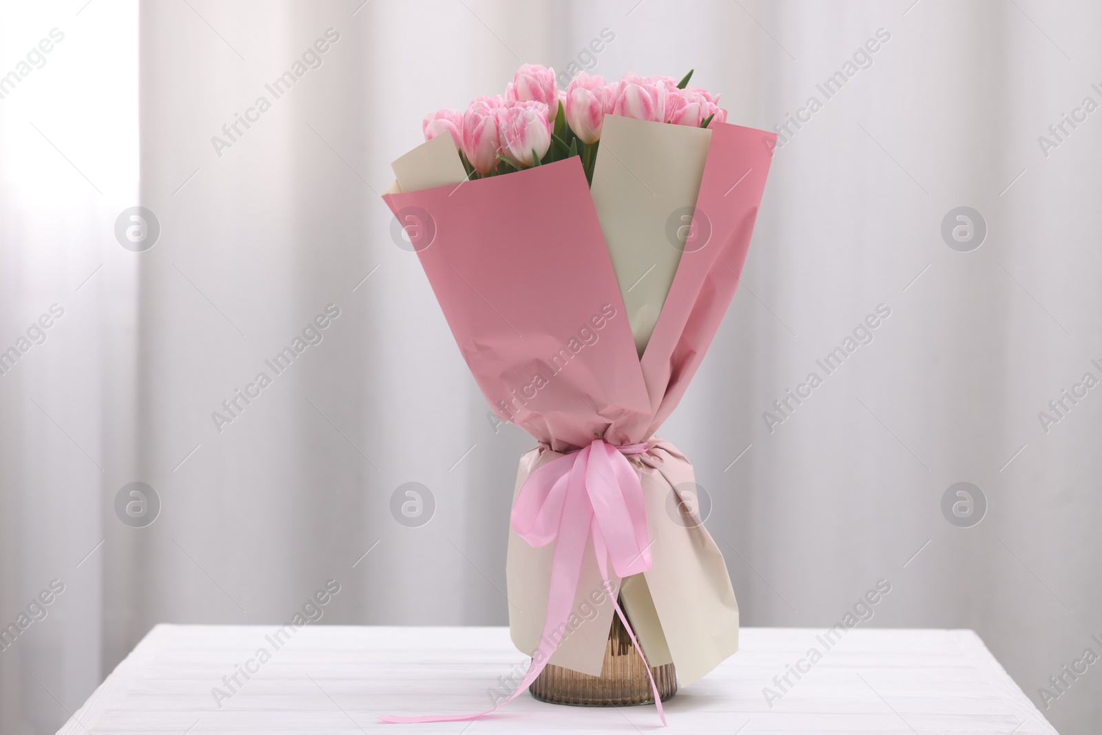 Photo of Beautiful bouquet of fresh pink tulips on table indoors