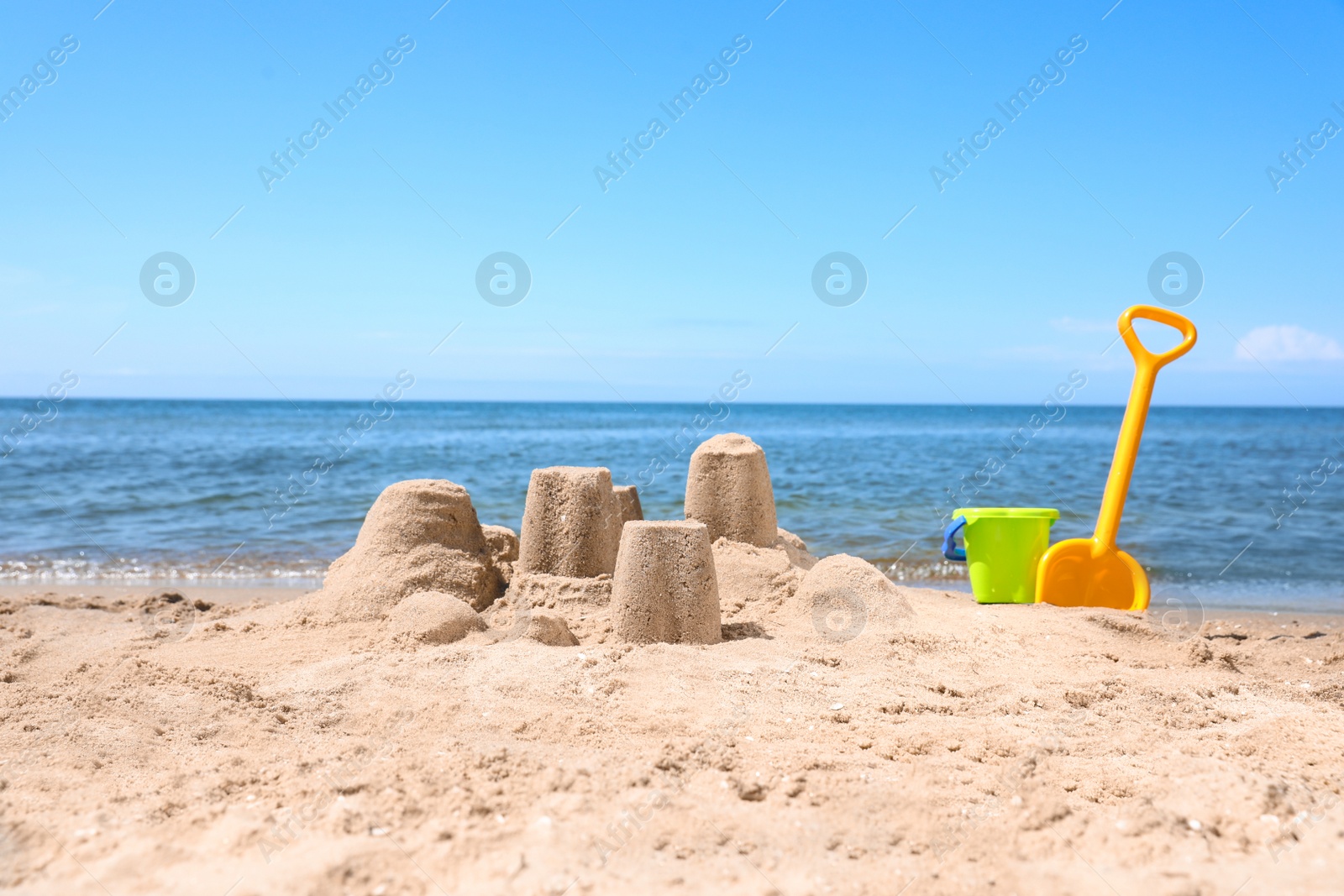 Photo of Little sand figures and plastic toys on beach near sea