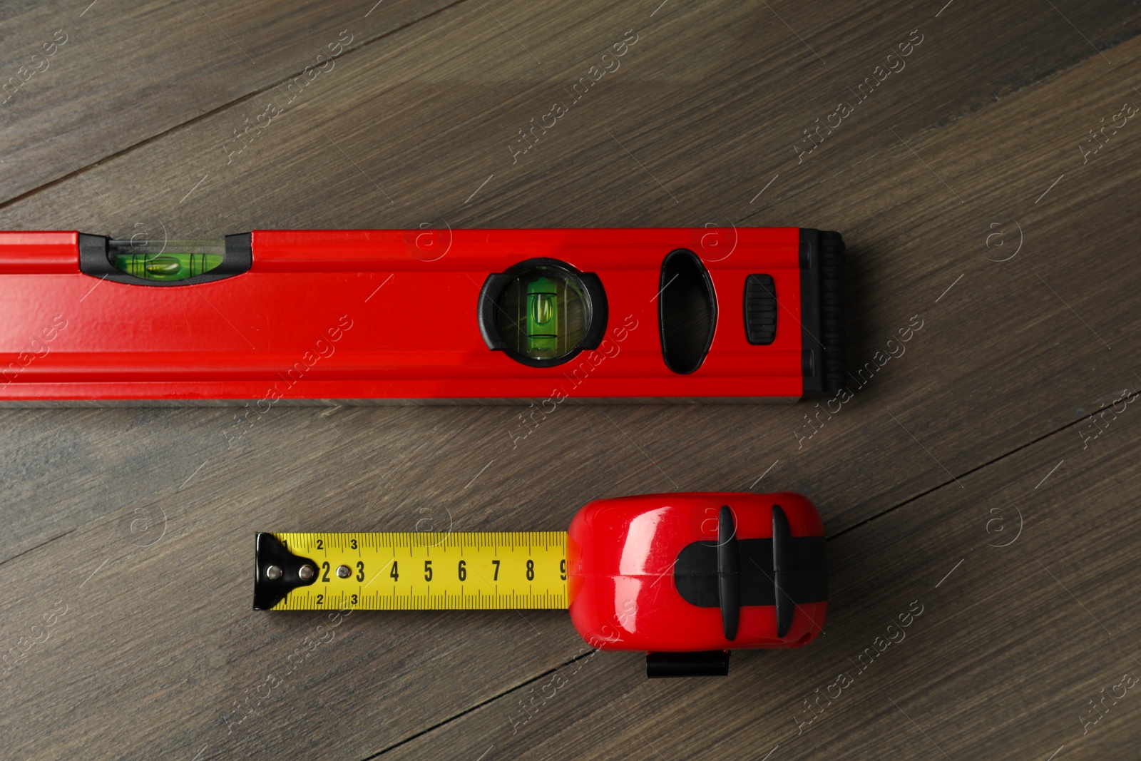 Photo of Building level and tape measure on wooden table, top view