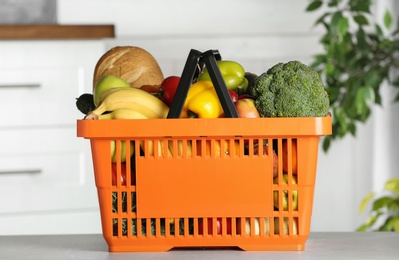 Shopping basket with grocery products on grey table indoors