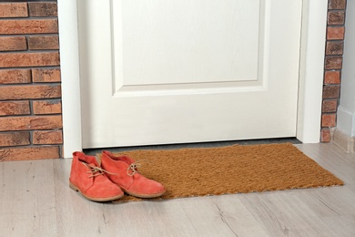 Photo of New clean mat with shoes near entrance door