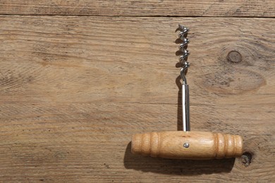 Photo of One corkscrew on wooden table, top view. Space for text