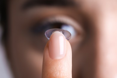 Photo of Closeup view of young woman putting contact lens in her eye