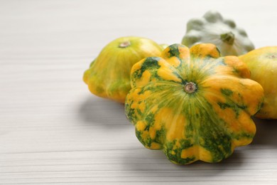 Photo of Fresh ripe pattypan squashes on white wooden table, closeup. Space for text
