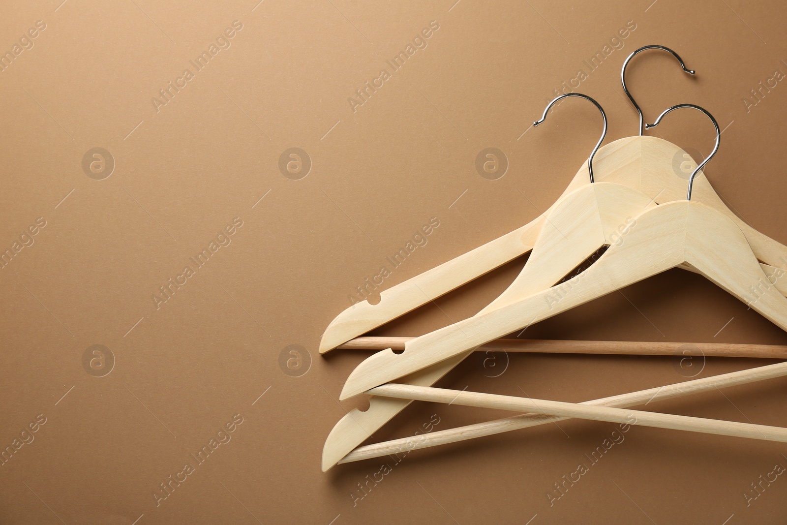 Photo of Wooden hangers on brown background, top view. Space for text