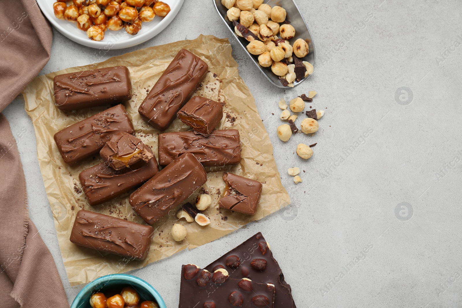 Photo of Delicious chocolate candy bars and nuts on light table, flat lay. Space for text