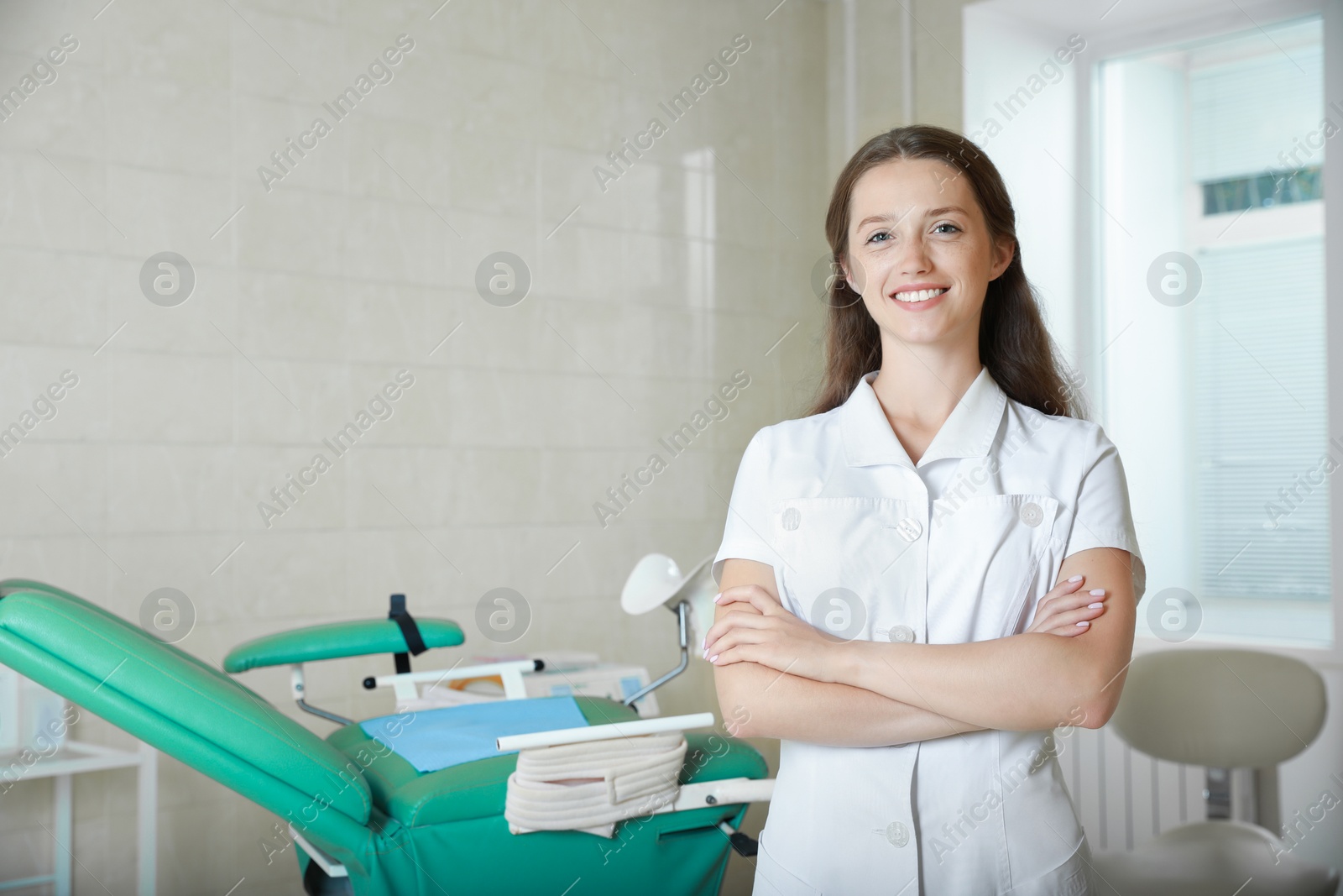 Photo of Portrait of smiling young gynecologist at workplace in clinic. Space for text