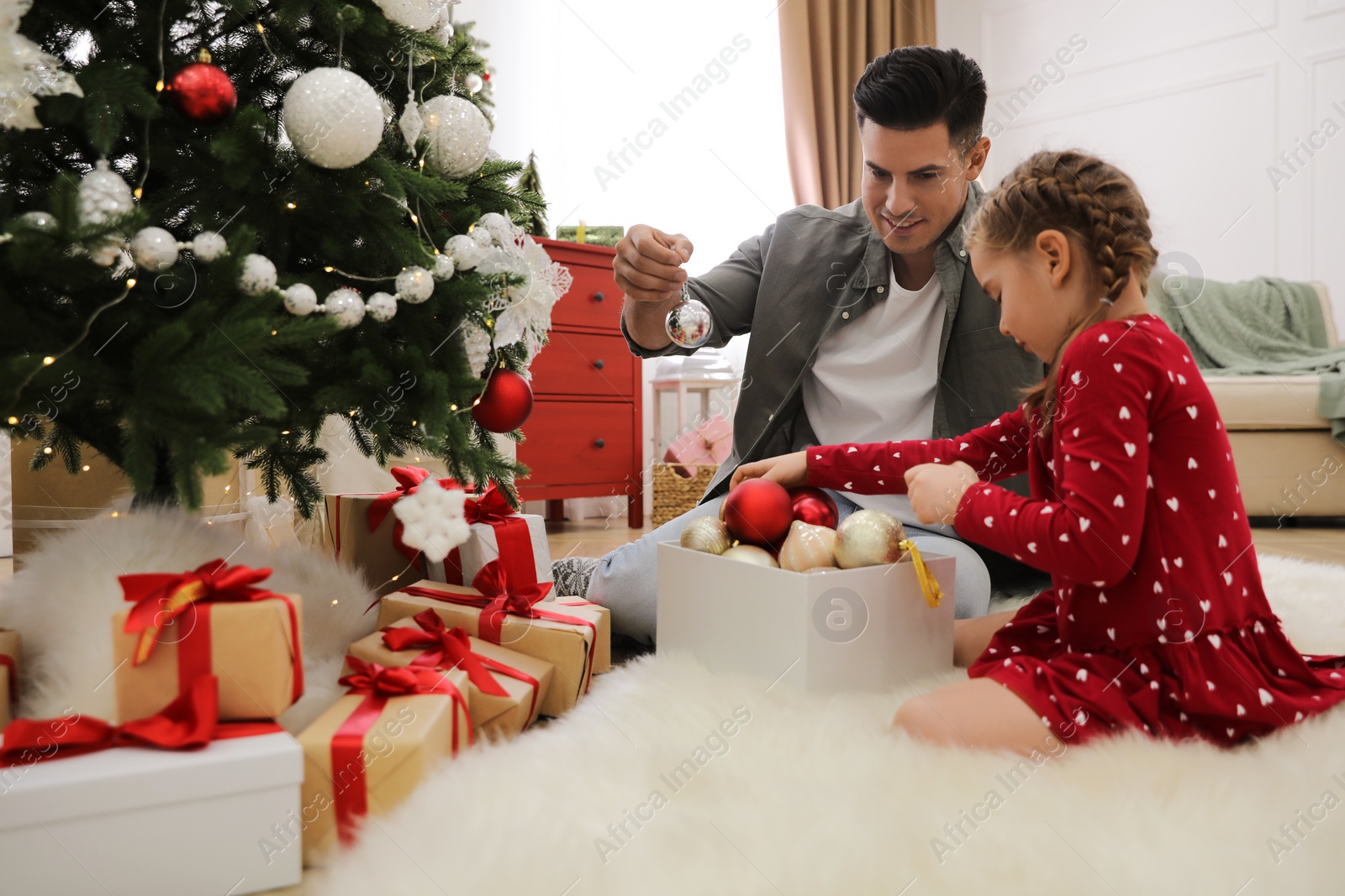 Photo of Father with his cute daughter decorating Christmas tree together at home