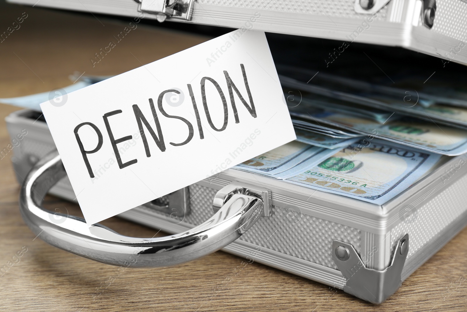 Photo of Card with word Pension and case of dollar banknotes on wooden table, closeup