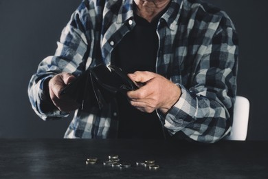 Image of Poor elderly man with empty wallet and coins at table, closeup