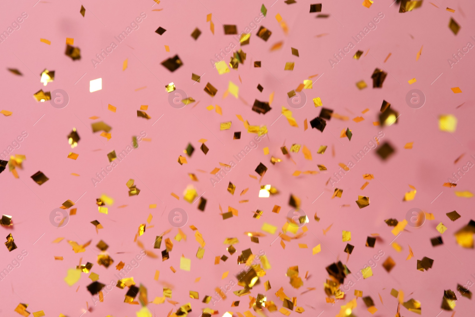 Photo of Shiny golden confetti falling down on pink background