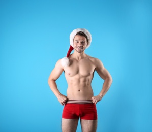 Photo of Shirtless young Santa Claus with sexy body on color background