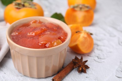 Bowl of tasty persimmon jam and ingredients on white textured table. Space for text