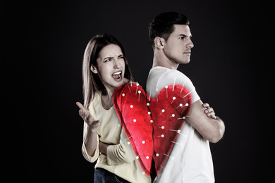 Double exposure of heart shaped cushion with sewing pins and couple quarreling on black background. Relationship problems
