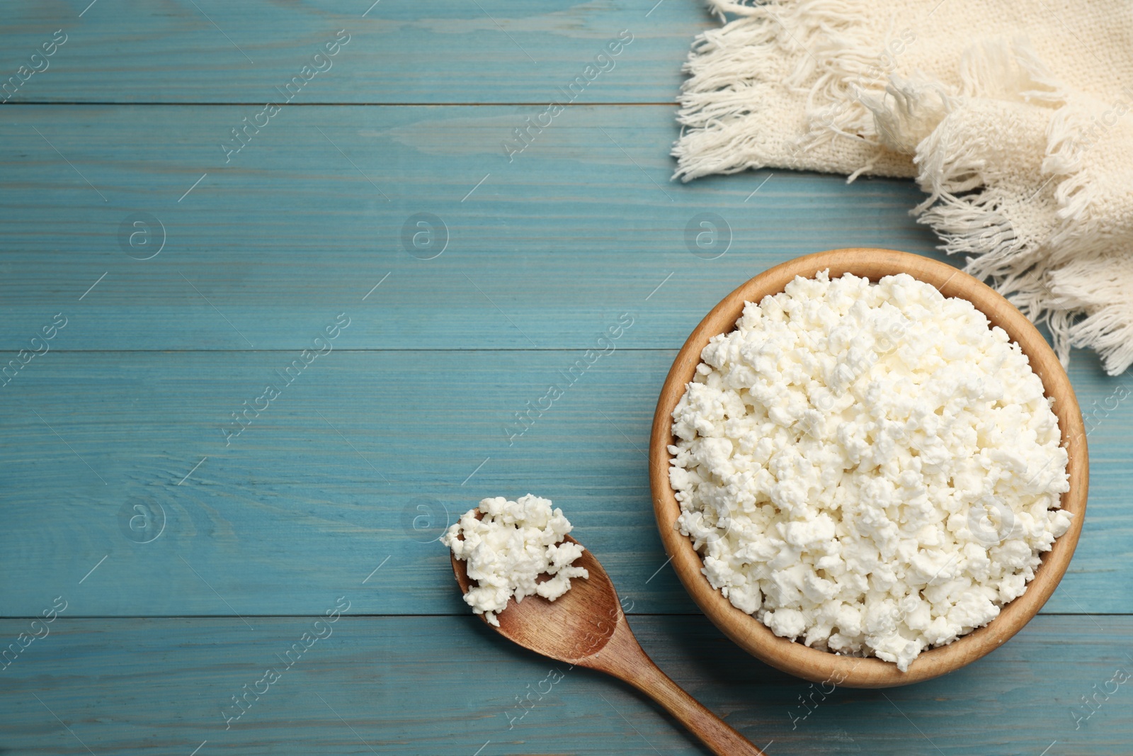Photo of Delicious fresh cottage cheese on blue wooden table, flat lay. Space for text