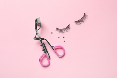 Photo of False eyelashes and curler on pink background, flat lay