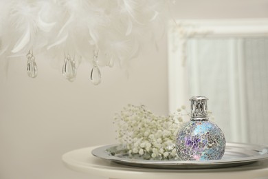 Stylish catalytic lamp with gypsophila on table in room, space for text. Cozy interior