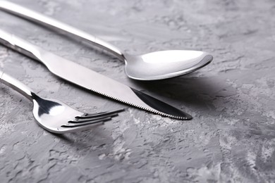 Photo of Stylish silver cutlery set on grey textured table, closeup