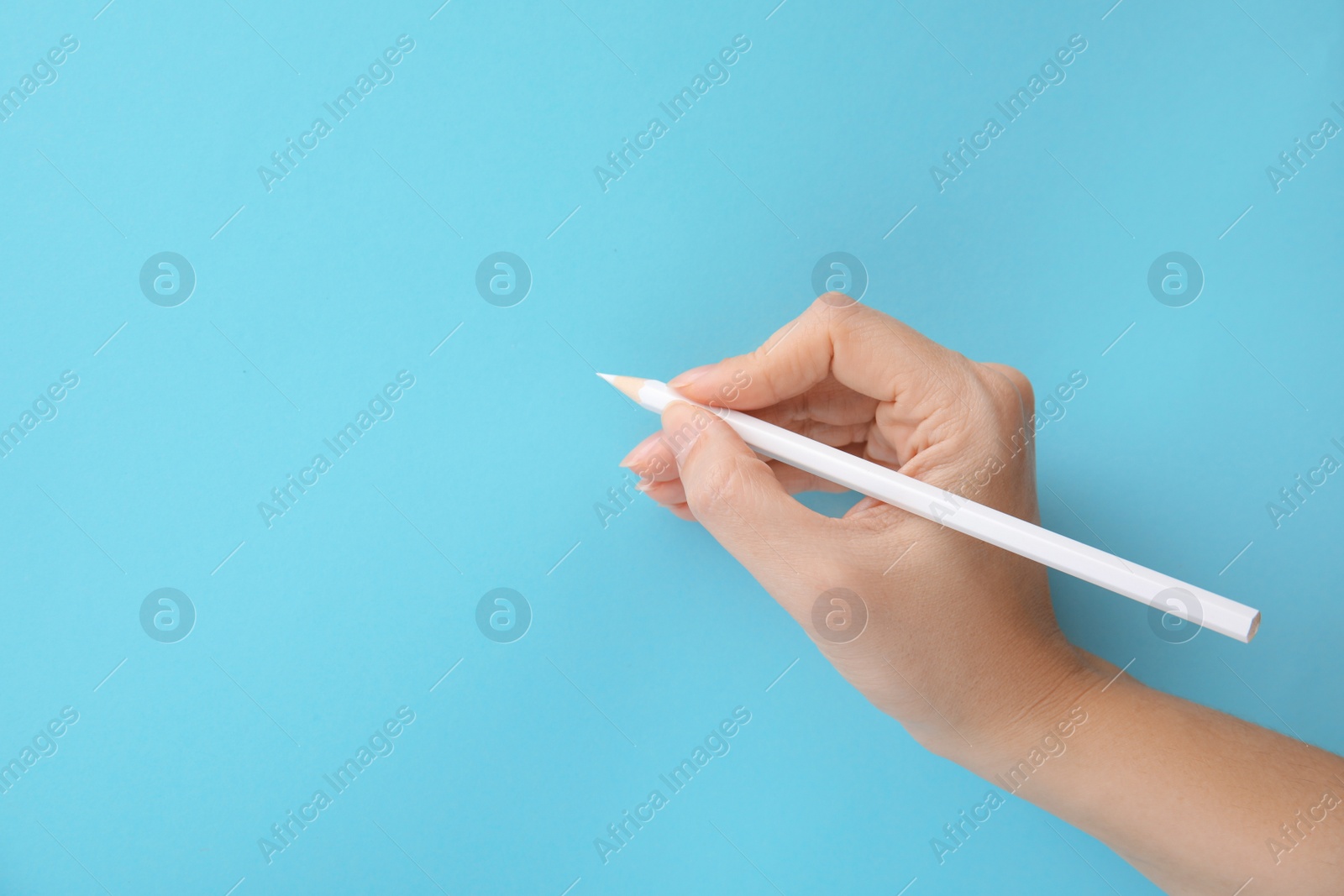 Photo of Woman with white pencil on light blue background, closeup. Space for text