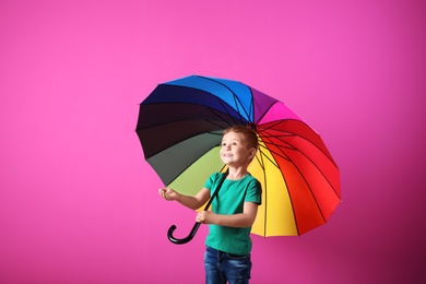 Little boy with rainbow umbrella on color background