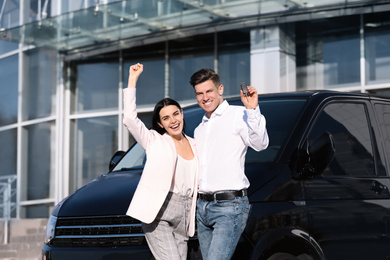 Photo of Happy couple with key near car on city street. Buying new auto