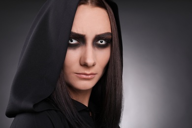 Photo of Mysterious witch with spooky eyes on dark background, closeup