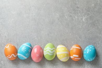 Photo of Flat lay composition of painted Easter eggs on color background, space for text