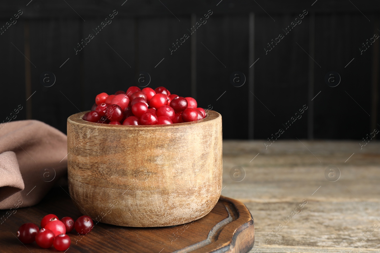 Photo of Cranberries in bowl on wooden table, space for text