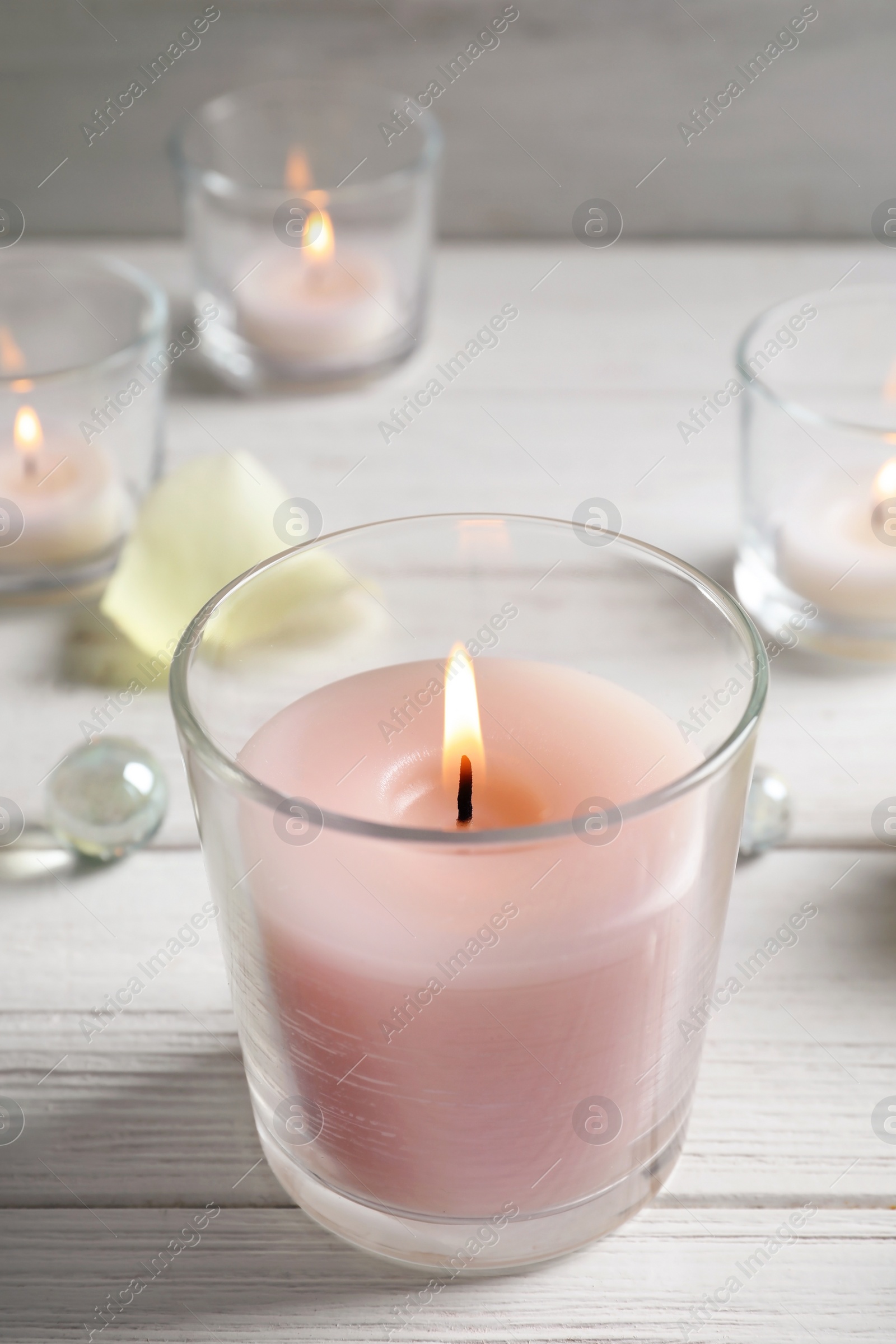 Photo of Beautiful burning wax candle in glass on table