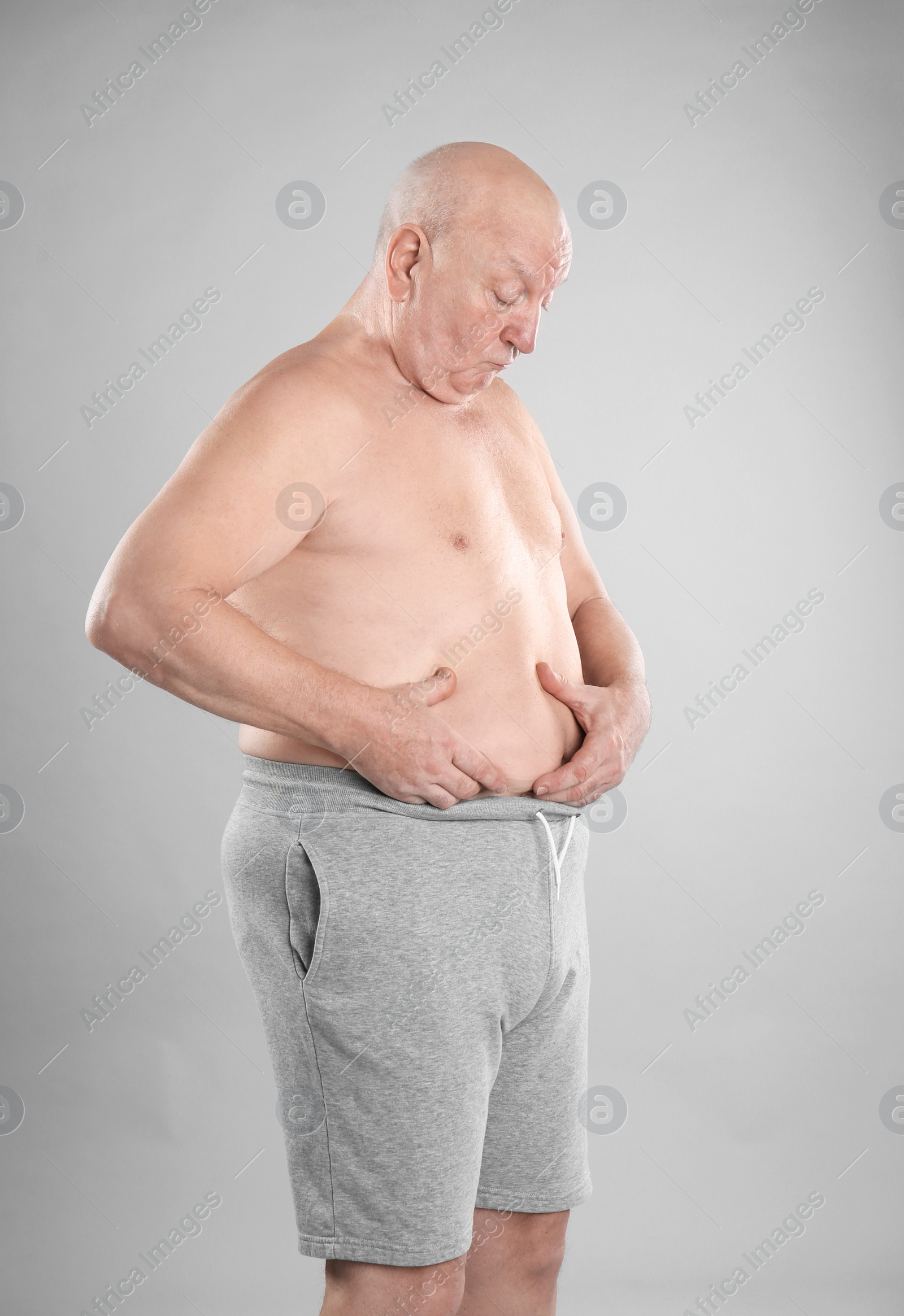 Photo of Fat senior man on grey background. Weight loss