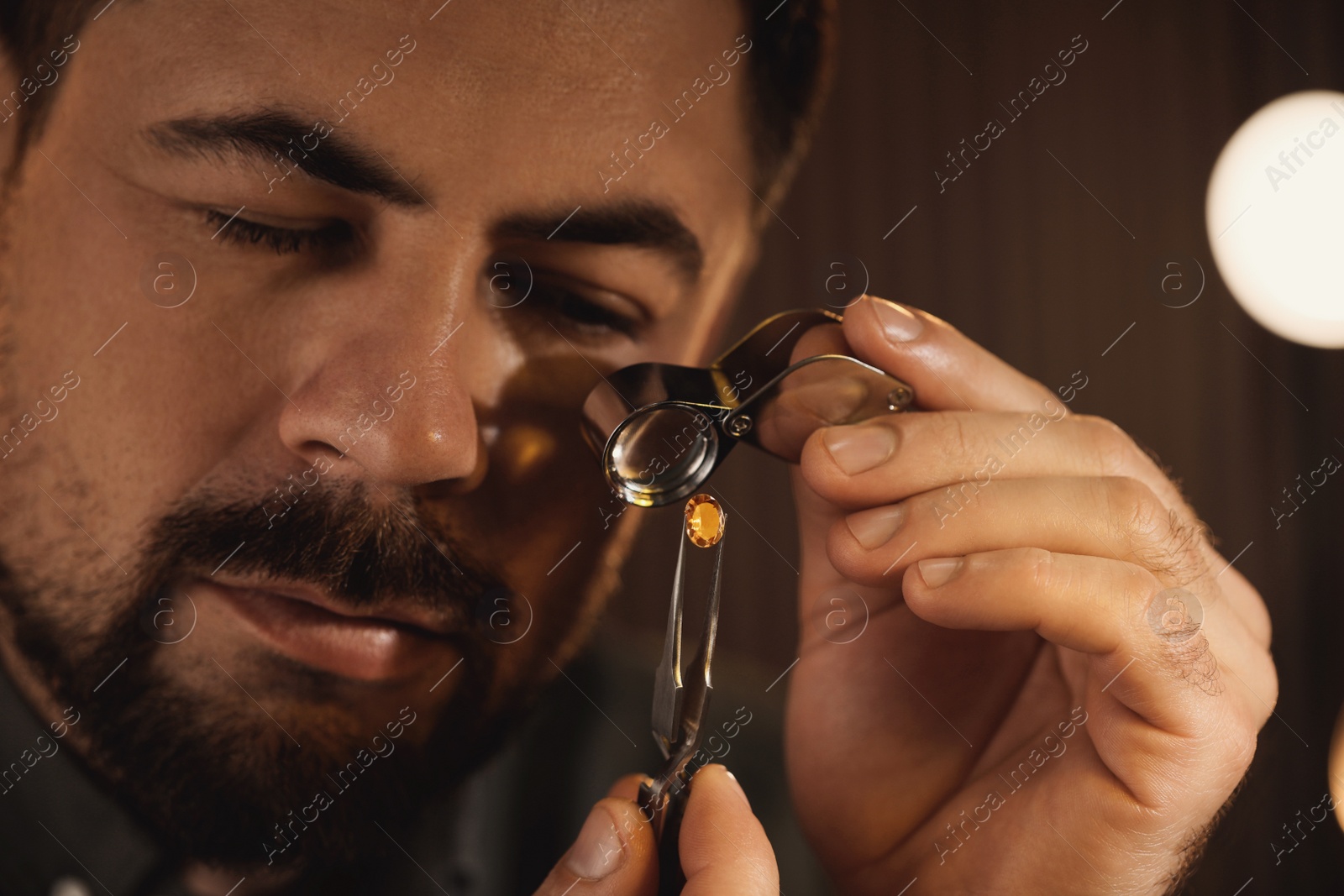 Photo of Jeweler working with gemstone on blurred background, closeup