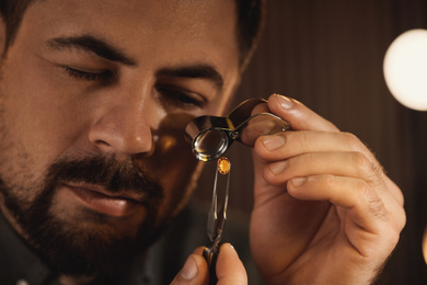 Jeweler working with gemstone on blurred background, closeup