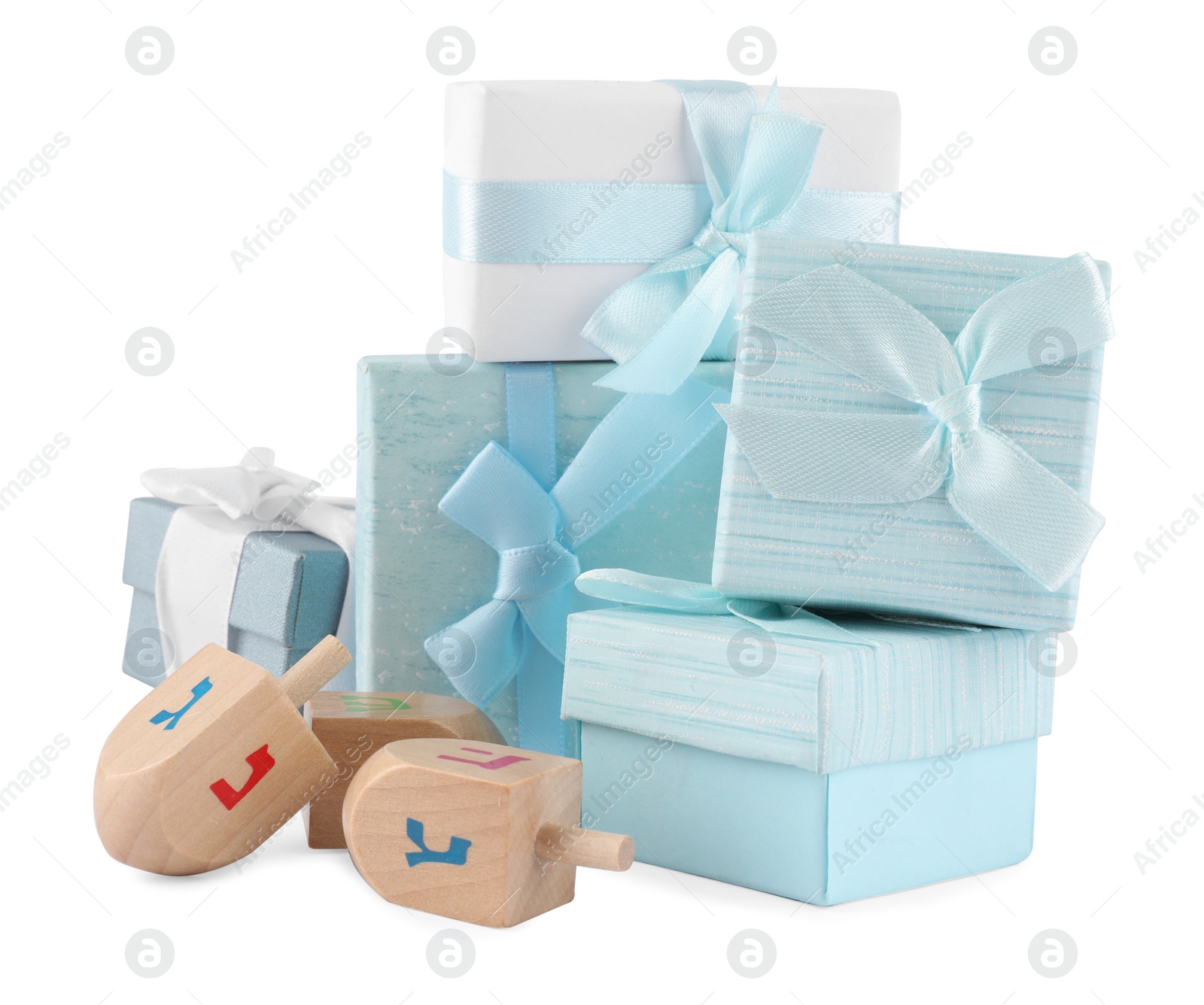 Photo of Hanukkah celebration. Wooden dreidels with jewish letters and gift boxes isolated on white