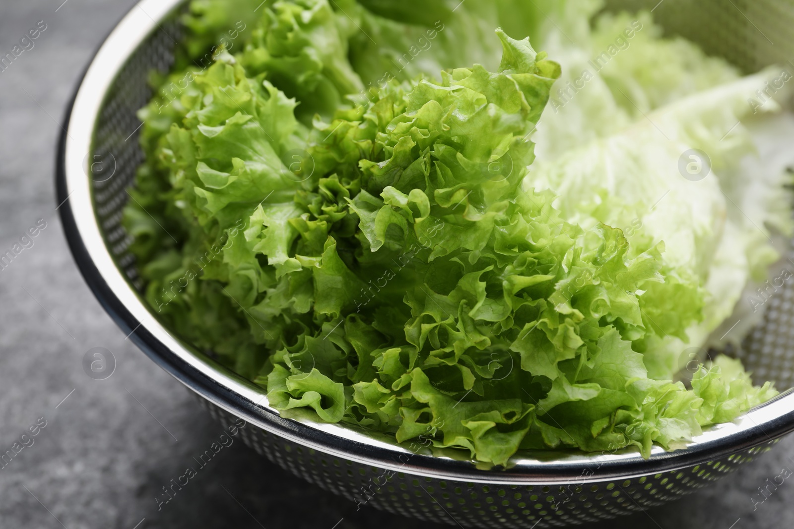 Photo of Fresh lettuce on stone table, closeup. Salad greens